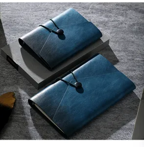 Detailed view of dark blue leather loose-leaf notebook with strap closure and button accent.