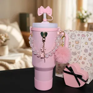 Pink insulated tumbler detail view featuring a cute bow straw cover, beaded strap, and fluffy pompom.