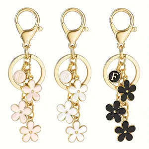 Gold initial letter flower keychain set with pink white and black floral bag charms.
