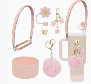 Detailed view of pink tumbler accessories, including braided strap, charm, pom-pom and straw cover.