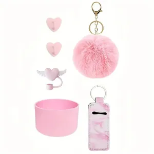Pink Stanley cup accessories set including pom pom keychain tumbler boot and straw cover.