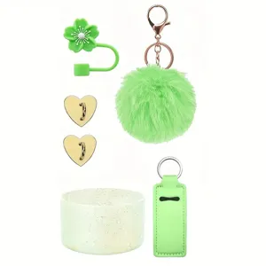 Stanley cup accessory detail view featuring green pompom, straw cover and sparkly silicone boot.