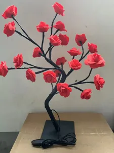 Gros plan de la lampe branche d'arbre rose LED avec des fleurs rouges pour déco romantique.