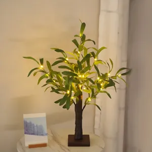 Detailansicht des dekorativen künstlichen Baums mit leuchtenden Lichterketten und grünen Blättern.