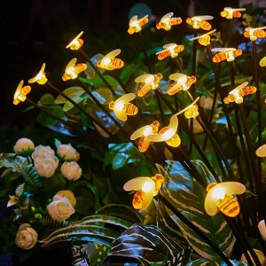 Detailansicht von solarbetriebenen Bienen-LED-Lichterketten im Gartengras leuchtend.
