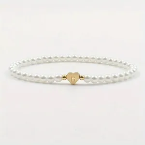 Fashion pearl beaded bracelet featuring a cute gold heart letter H charm detail close up.