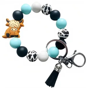 Détail de porte-clés en perles de silicone avec un beau charme de highland et pompon.
