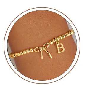 Close-up view of the lovely gold beaded stretch bracelet with bow and letter B charm.