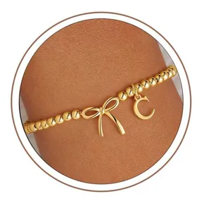 Gold bead bracelet detail featuring a charming bow and initial letter C pendant design.