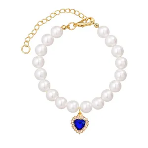 Detailed view of pearl pet necklace with sparkling blue heart pendant and gold extension chain.