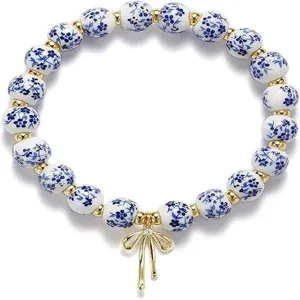 Ceramic blue and white porcelain beaded bracelet with gold bow pendant and rhinestone details.