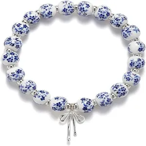 Blue and white porcelain style ceramic beaded bracelet with cute metal bow pendant details.
