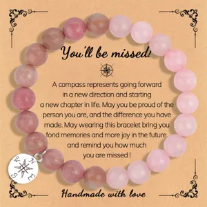 Pulsera de cuentas de piedra natural rosa con dije de brújula y detalles de tarjeta.