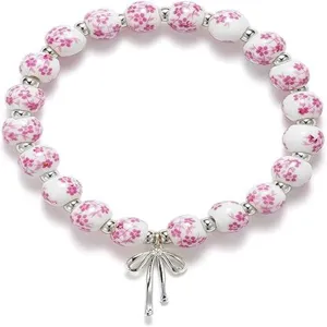 Detailed close-up view of the ceramic floral bead stretch bracelet featuring a bow charm.