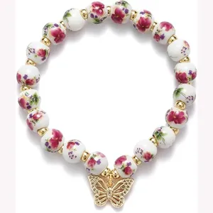 Ceramic floral bead bracelet with gold spacer beads and crystal butterfly charm stretch