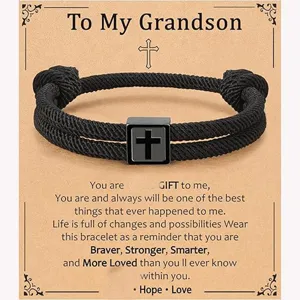 Detailed view of handmade black braided Milan rope bracelet featuring stainless steel cross charm.