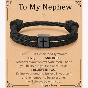 Detailed close-up of the black woven rope bracelet featuring a stainless steel cross charm.