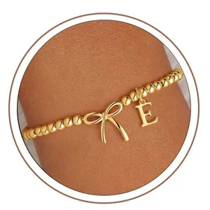 Elegant gold beaded stretch bracelet featuring a cute bowknot charm and initial letter E.