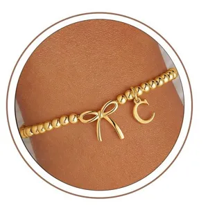 Gold beaded stretch bracelet featuring a cute bow charm and initial letter C pendant.