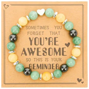 Close-up detail of beaded bracelet with green and yellow stones on inspirational message card.
