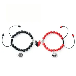 Detail shot of couple magnetic stone bracelets with heart pendants for custom logo engraving.