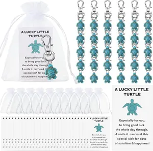 Detail view of turquoise turtle keychain charms set with organza gift bags and blessing cards.