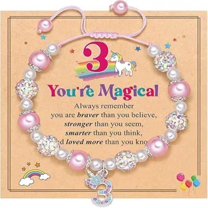 Detailed view of kids pink beaded bracelet with unicorn charm and number three card.