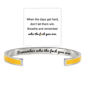 Detailed view of the stainless steel cuff bracelet with yellow enamel and engraved quote.
