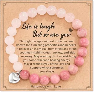 Close-up detail of natural stone beaded bracelet with inspirational card and heart pendant.