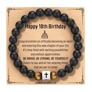 Detalle de pulsera de obsidiana mate con dije de cruz de acero y piedra de ojo de tigre.