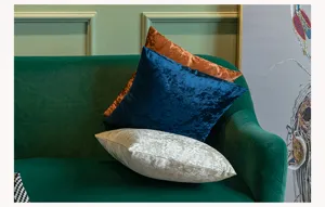 Close-up detail of soft velvet pillowcases stacked on a green sofa, cozy home decor setting.