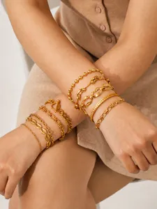 Close-up detail of multi-layer gold stainless steel chain bracelets set worn on wrists elegantly.