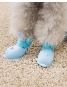 Primo piano di stivali da pioggia per animali in silicone design balena blu su zampe di cucciolo.