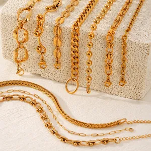 Detail view of various gold stainless steel chains and bracelets with textured link designs.