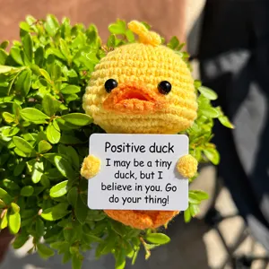Detailed shot of handmade crochet cute yellow duck holding positive message encouragement card.
