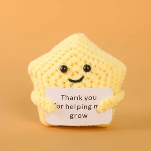 Detailed close-up of handmade crochet yellow star plush doll holding a cute thank you card.