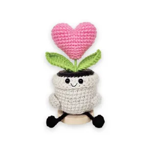 Handmade crochet heart potted plant detail showing cute smiley face and soft wool green leaves.