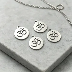 Gros plan de quatre pendentifs breloques symbole Om en acier inoxydable sur pierre grise.