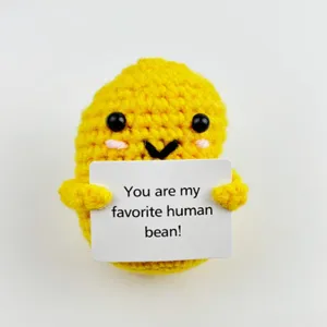 Primo piano di peluche fagiolo giallo all'uncinetto fatto a mano con biglietto.