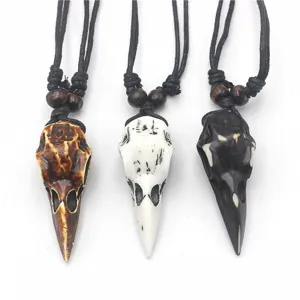 Closeup of three bird skull resin pendant necklaces in brown white and black colors with cords