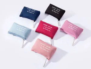 Detailed view of multiple canvas zipper coin purses in assorted colors with printed lettering.