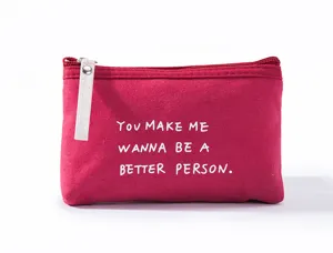 Close-up detail of the red canvas zipper pouch showing white quote print and zipper pull.