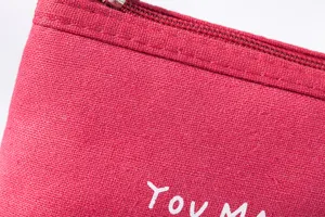 Red canvas coin purse detail close-up showing durable fabric texture and smooth metal zipper.