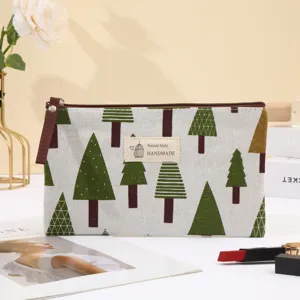 Detailed close-up of the canvas cosmetic pouch with green tree print and handmade label.