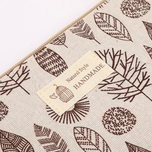 Close-up detail of fabric cosmetic makeup bag with leaf pattern and handmade woven label.