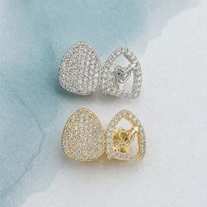 Detailed view of hip hop zircon grillz teeth, double gold and silver heart pierced tooth caps.