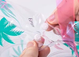 Pochette de maquillage transparente en PVC avec fermeture à pression et motif tropical.