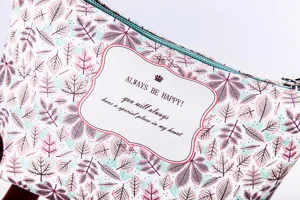 Close-up detail of cosmetic bag with leaf pattern and english text label, elegant pouch.