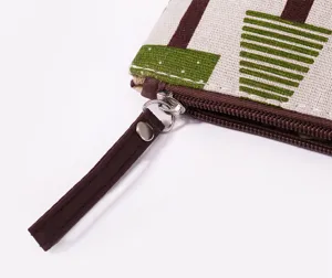 Detail van canvas cosmetische tas met metalen rits en bedrukt boompjespatroon.
