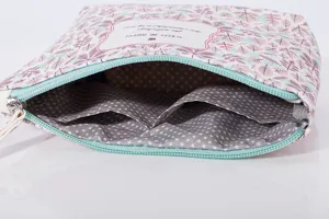 Detailed view of cosmetic bag with leaf pattern, zipper closure and polka dot inner lining.